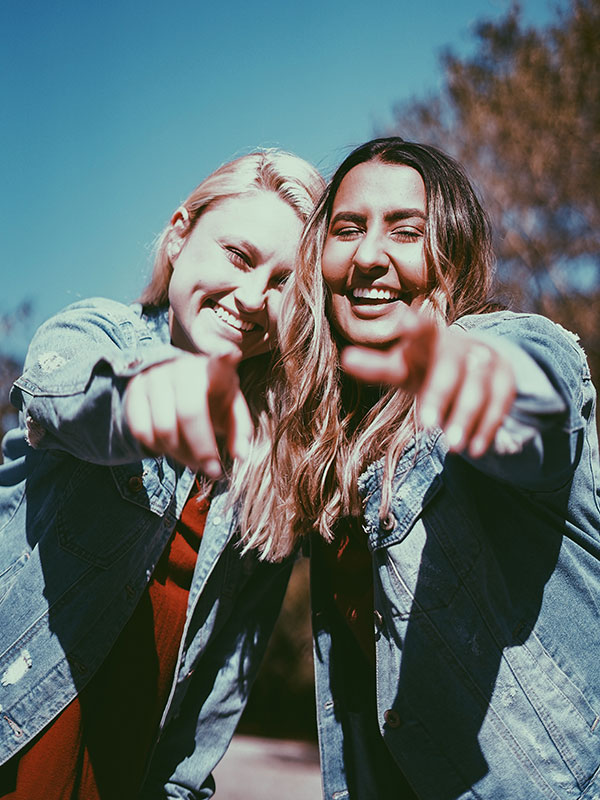 Young-women-smiling-and-poitning-to-camera