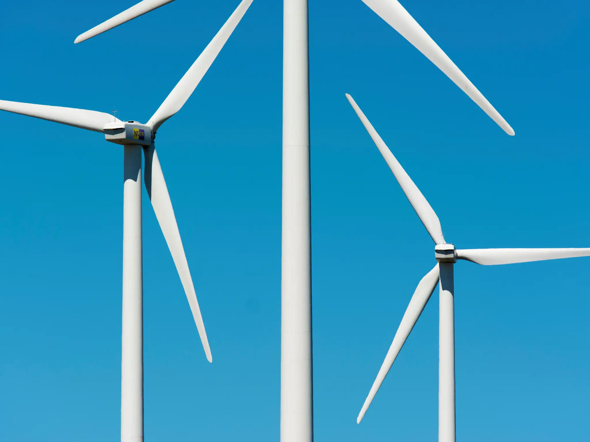 3 wind farm windmills against a blue sky